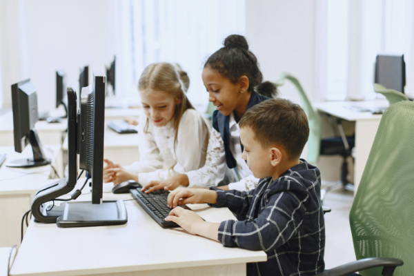 Photo of two girls and a boy using a computer